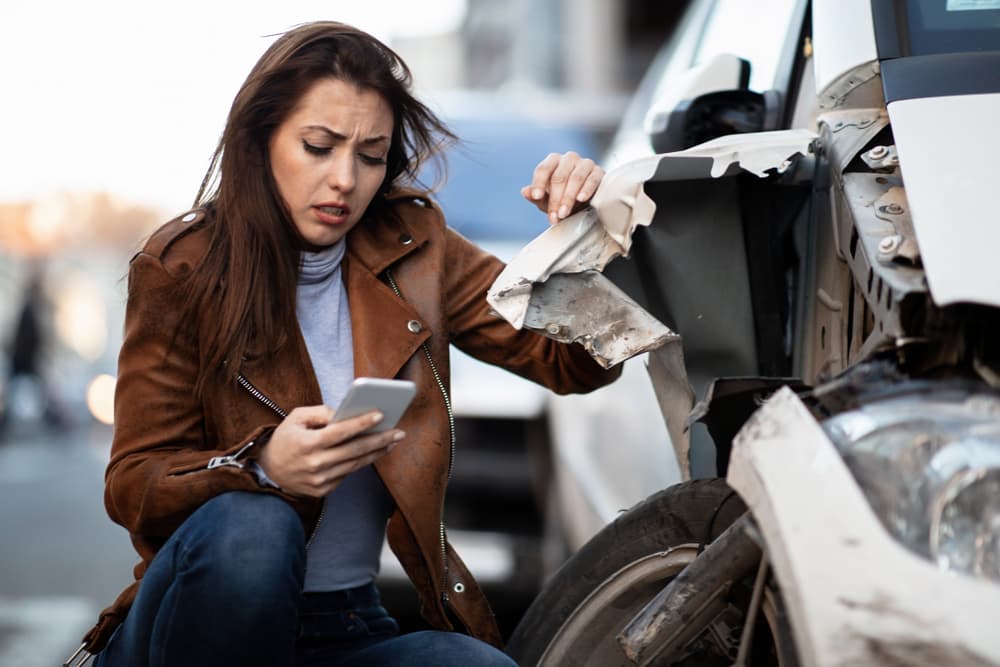 Unhappy woman on phone, texting after the dangerous car accident in Tulsa, Oklahoma.
