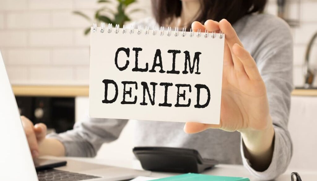 Professional woman displaying a card with 'Claim Denied' text