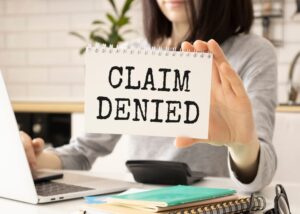 Professional woman displaying a card with 'Claim Denied' text