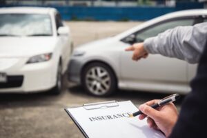 An insurance agent is inspecting a damaged vehicle and completing a report for a claim form after a traffic accident, illustrating the concept of traffic accidents and insurance.