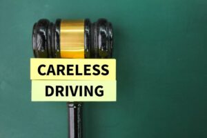 A judge's gavel poised beside colored paper bearing the words "careless driving," symbolizing the concept of reckless driving.