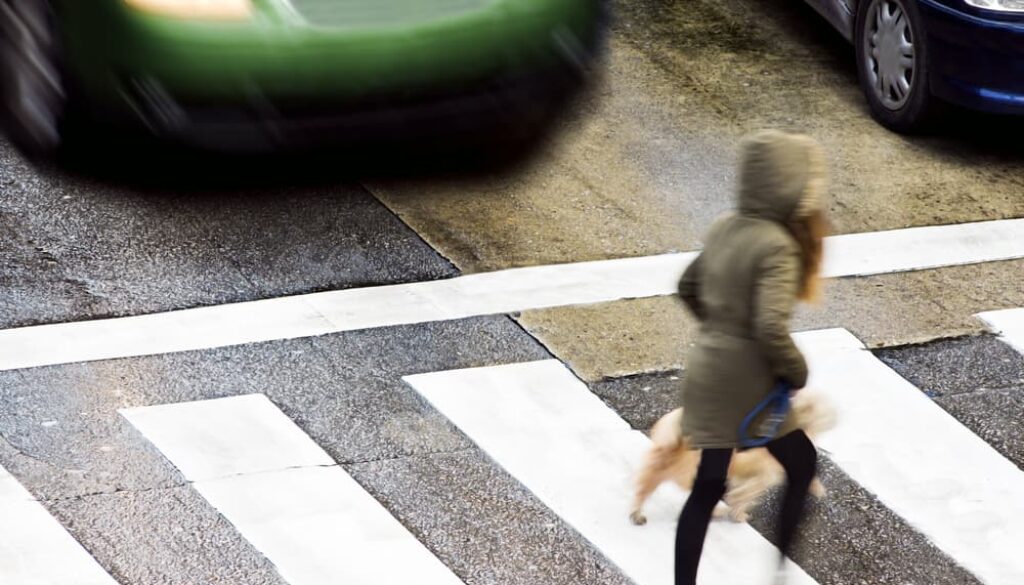 A dangerous situation at a city street crosswalk with people.