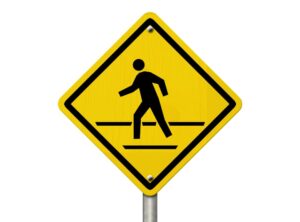 A road warning sign isolated on a white background, featuring a man walking symbol and the message "Caution: Crosswalk Present." 