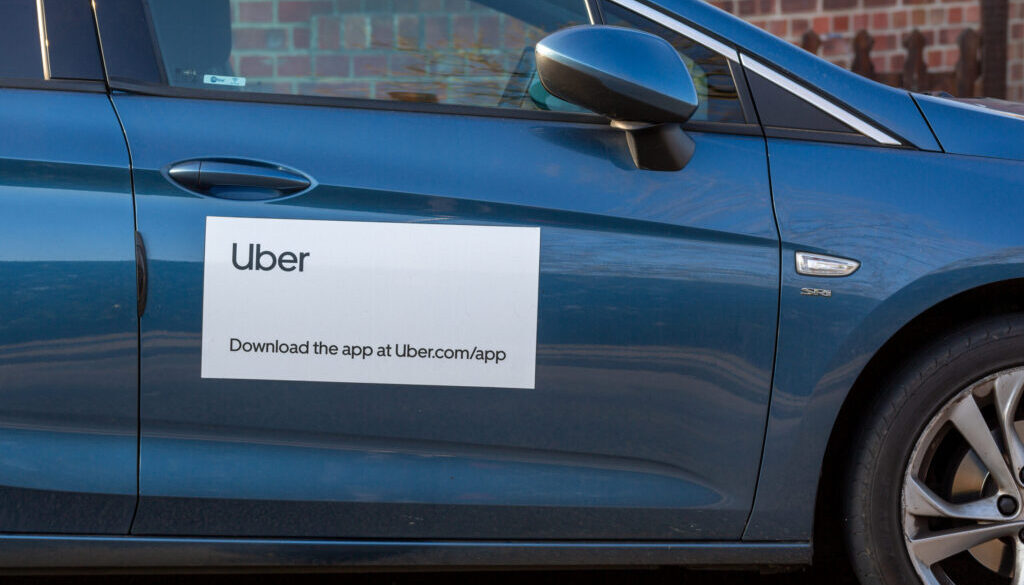 A blue car with an Uber logo and app download information on the door, representing rideshare services in Tulsa.