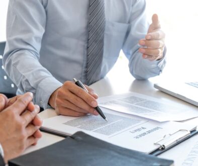 Client discussing refusing an insurance offer with an agent, reviewing policy details at a desk with documents and a laptop.