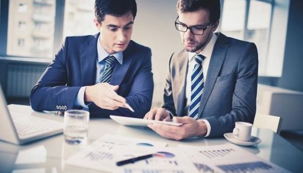 Two professional attorneys reviewing documents and data at a business meeting.