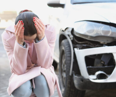 Stressed woman after car accident in Tulsa with vehicle damage, needing Uninsured Motorist Insurance assistance