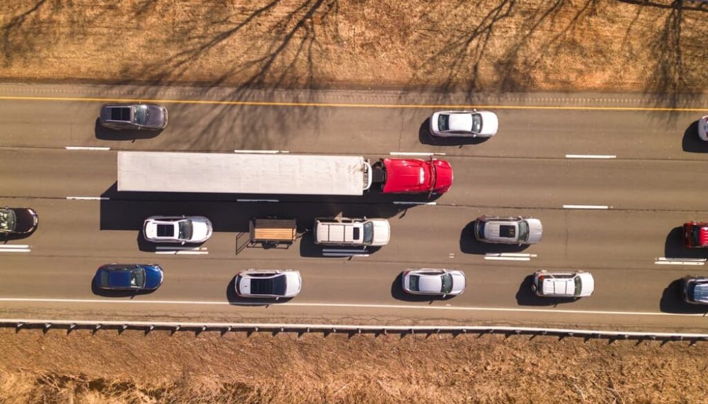 Aerial view of a red semi-truck surrounded by cars on an Oklahoma highway