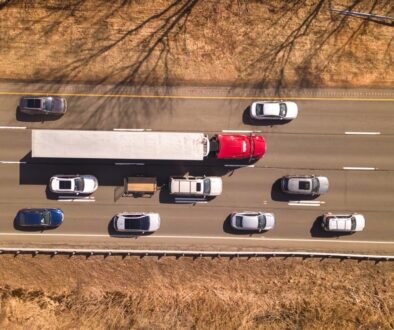 Aerial view of a red semi-truck surrounded by cars on an Oklahoma highway