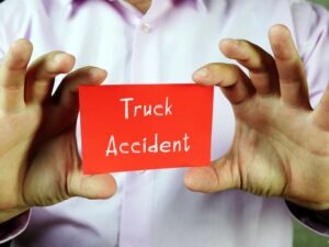 Person holding a red card with the words “Truck Accident”