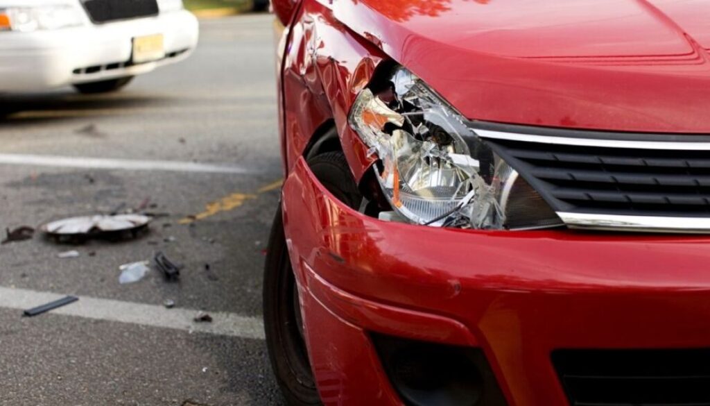 Damaged red car with broken headlight after a Tulsa car accident