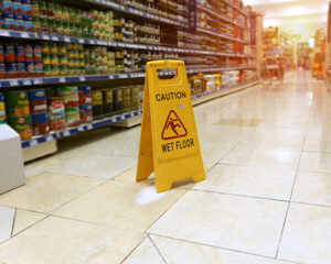 Wet floor sign inside a Tulsa grocery store, showing a common hazard in slip and fall injury cases handled by experienced Tulsa personal injury lawyers.
