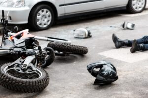 Motorcycle lies on pavement with scattered debris after a crash near multiple vehicles in Oklahoma.