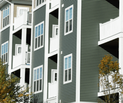 Exterior of a mid-rise apartment complex in Oklahoma with siding, balconies, and fall trees