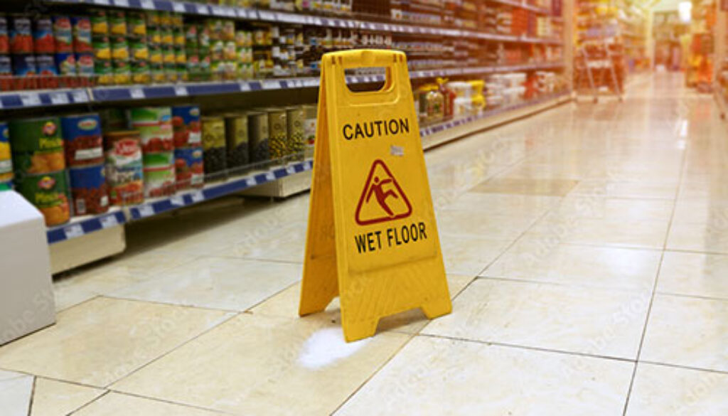 Wet floor caution sign in a grocery store aisle, representing common types of premises liability accidents