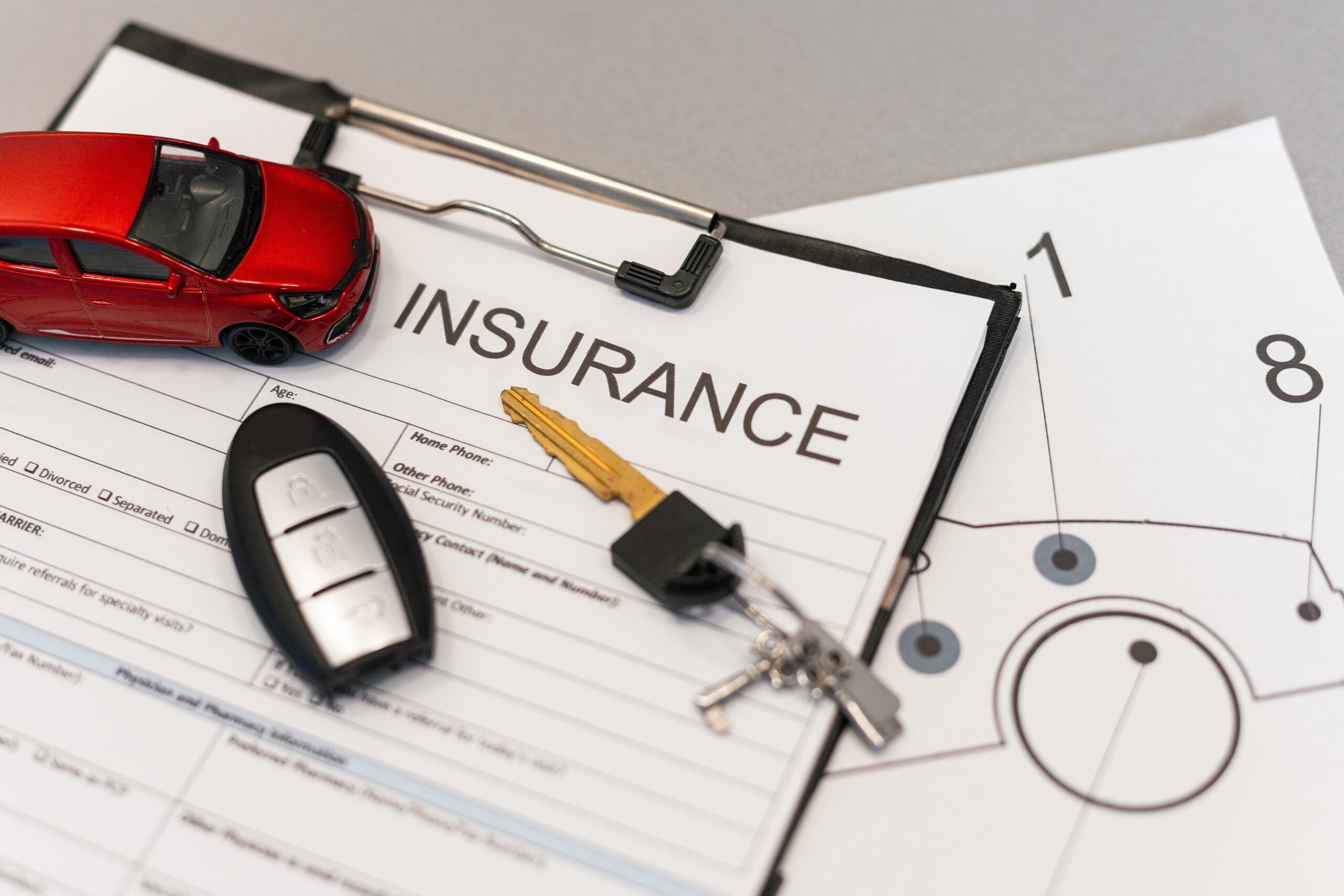 Auto insurance policy form with car key and miniature car