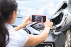 Woman taking photo of vehicle damage after Owasso car crash