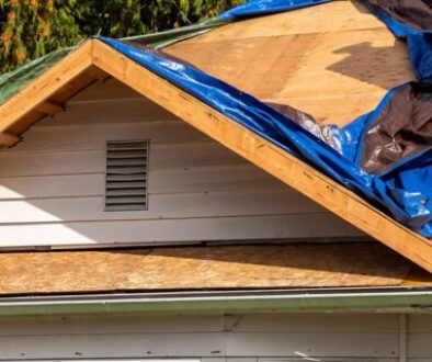 Storm-damaged Oklahoma home with tarped roof and exposed plywood after denied insurance claim”